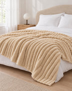 Plaid polaire côtelé Douillette, coloris beige sable, sur un lit, chambre claire