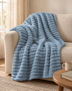 Plaid polaire côtelé Douillette, coloris bleu brume, sur un canapé