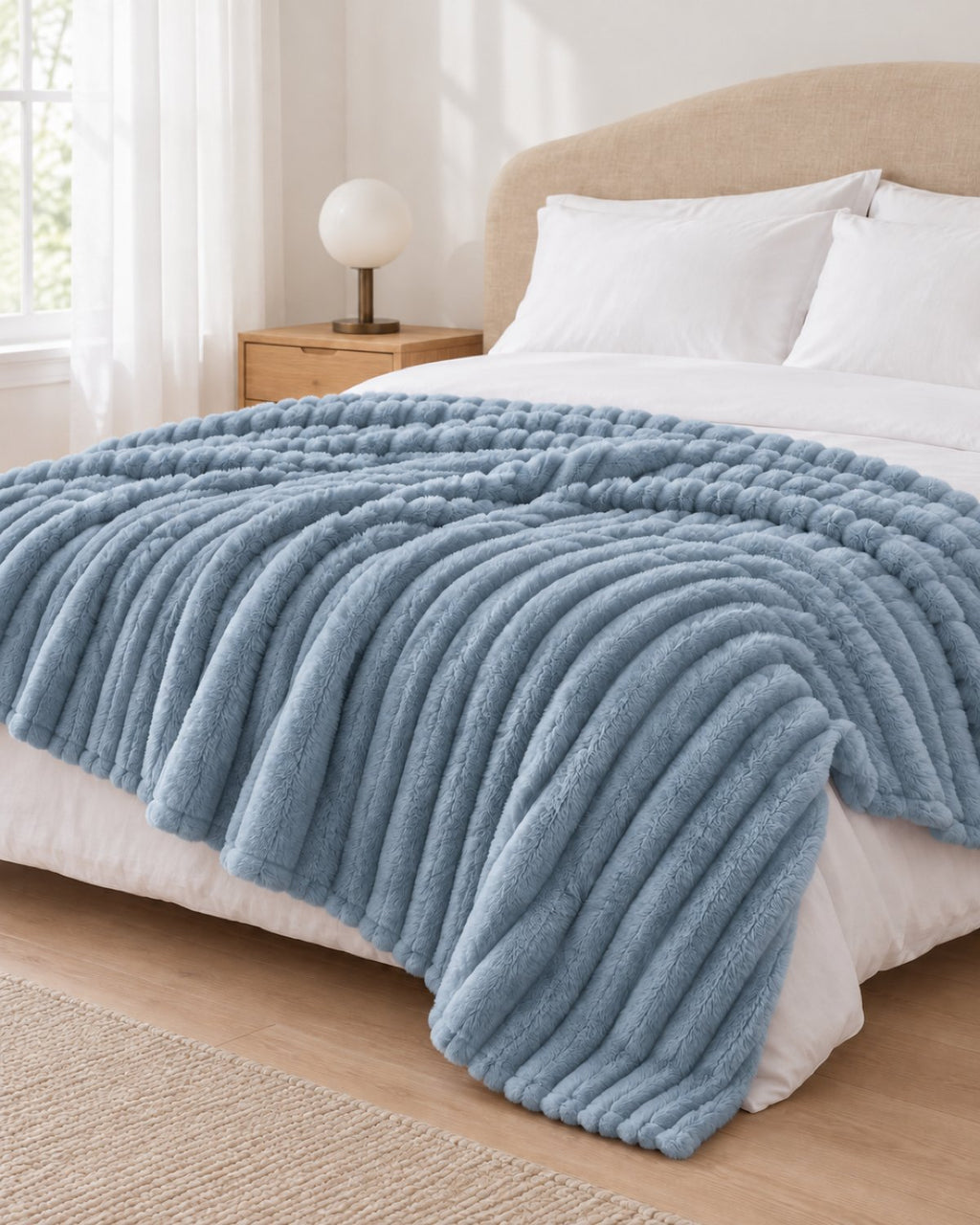 Plaid polaire côtelé Douillette, coloris bleu brume, sur un lit, chambre claire