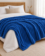 Plaid polaire côtelé Douillette, coloris bleu roi, sur un lit, chambre en bois