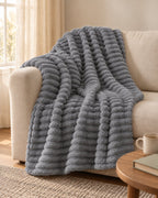 Plaid polaire côtelé Douillette, coloris gris anthracite, sur un canapé