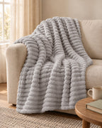 Plaid polaire côtelé Douillette, coloris gris perle, sur un canapé