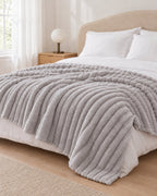 Plaid polaire côtelé Douillette, coloris gris perle, sur un lit, chambre claire