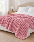 Plaid polaire côtelé Douillette, coloris rose poudré, sur un lit, chambre claire
