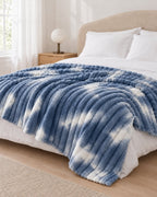 Plaid polaire côtelé Douillette, coloris tie-dye bleu denim, sur un lit, chambre claire