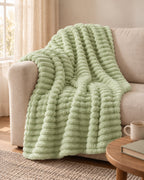 Plaid polaire côtelé Douillette, coloris vert sauge, sur un canapé